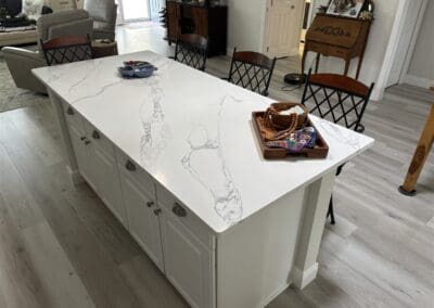 white quartz with grey veins countertop on a kitchen island with a counter overhang to seat 3 people