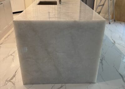 kitchen island with Cristallo Extra Quartzite countertops and matching waterfall sides that are precisely mitered 6 cm edges